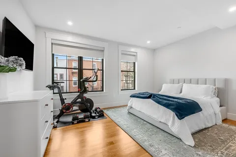 a bedroom with a bed a flat screen tv and a large window