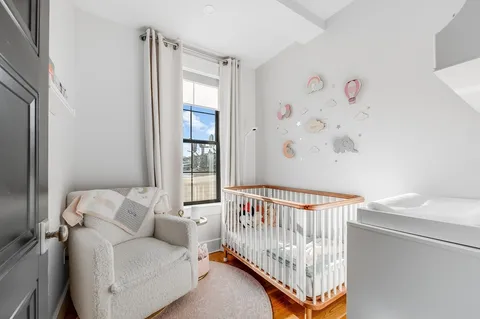 a view of a bedroom with furniture and baby crib