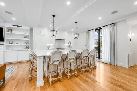a kitchen with stainless steel appliances kitchen island granite countertop a table chairs and a wooden floor