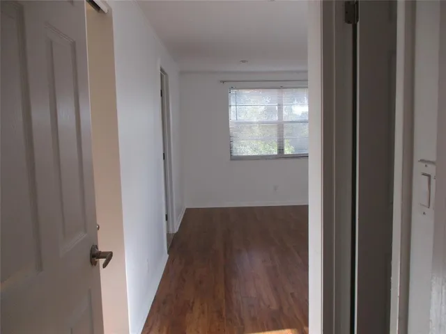 a view of a hallway with wooden floor and closet