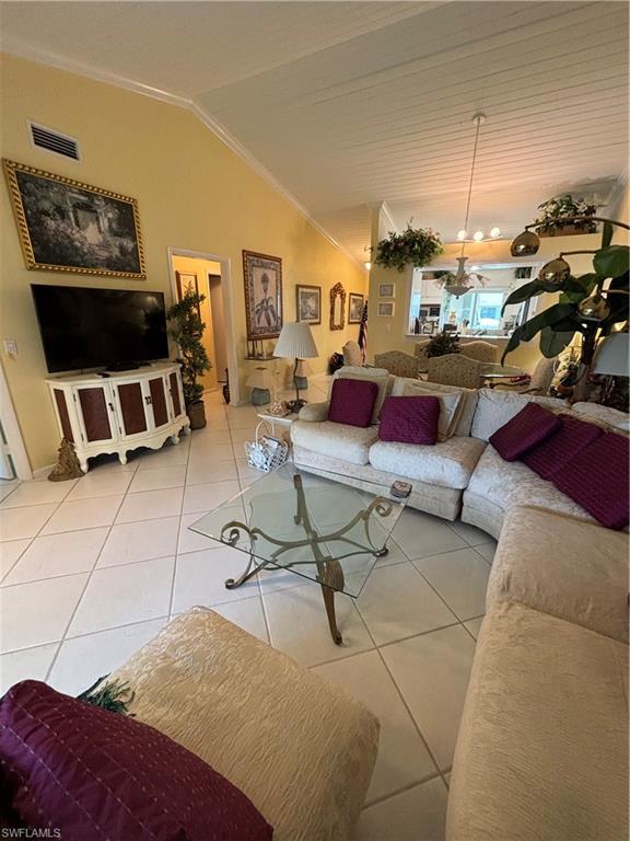 Undisclosed Address Naples, FL 34112 - Photo 12 of 35 Living room with visible vents, vaulted ceiling, crown molding, an inviting chandelier, and light tile patterned floors