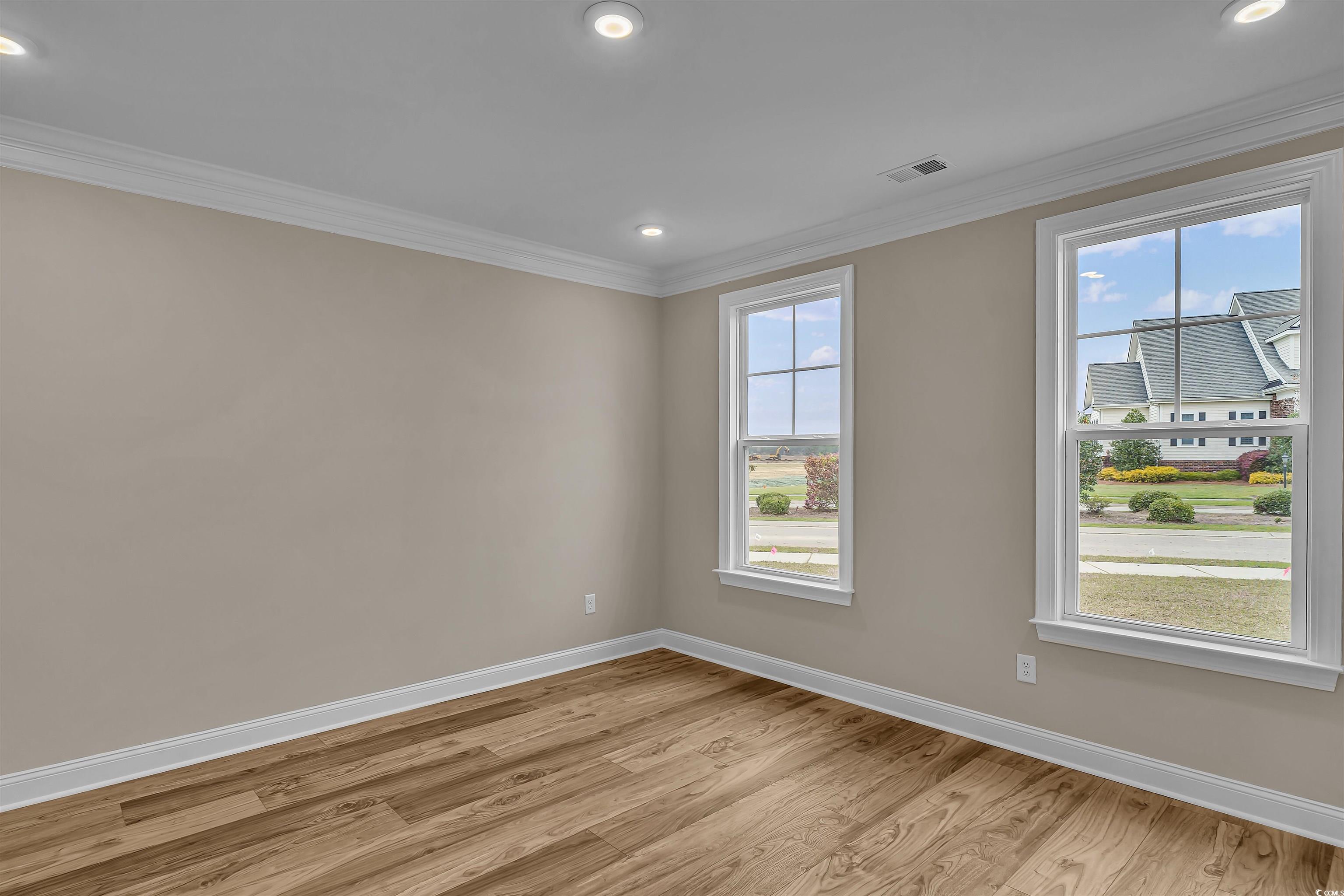 550 Beachside Circle Calabash, NC 28467 - Photo 12 of 39 Spare room with a wealth of natural light, crown molding, and light hardwood / wood-style floors
