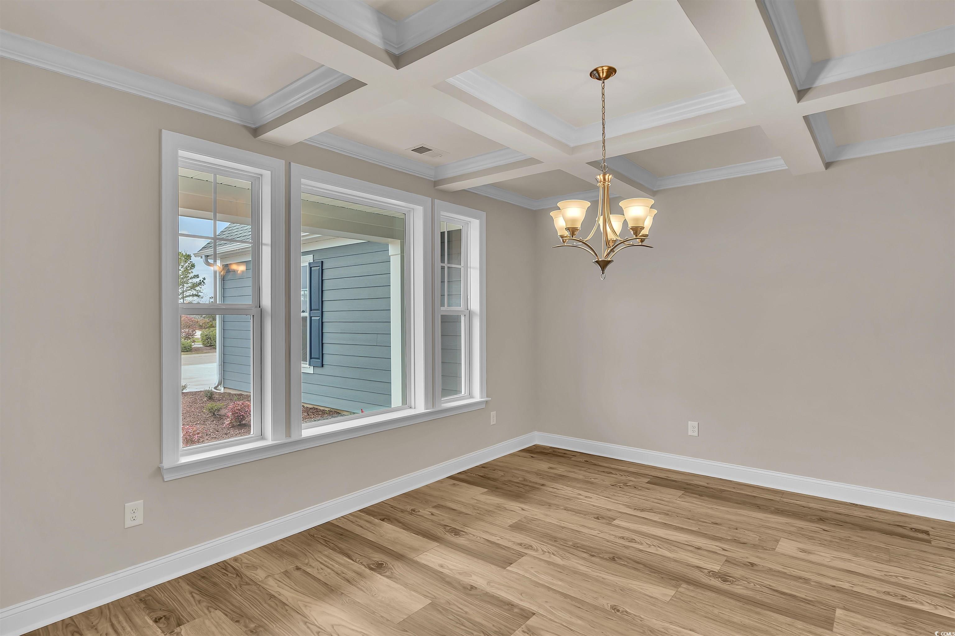 550 Beachside Circle Calabash, NC 28467 - Photo 14 of 39 Empty room featuring ornamental molding, coffered ceiling, beamed ceiling, a chandelier, and hardwood / wood-style floors