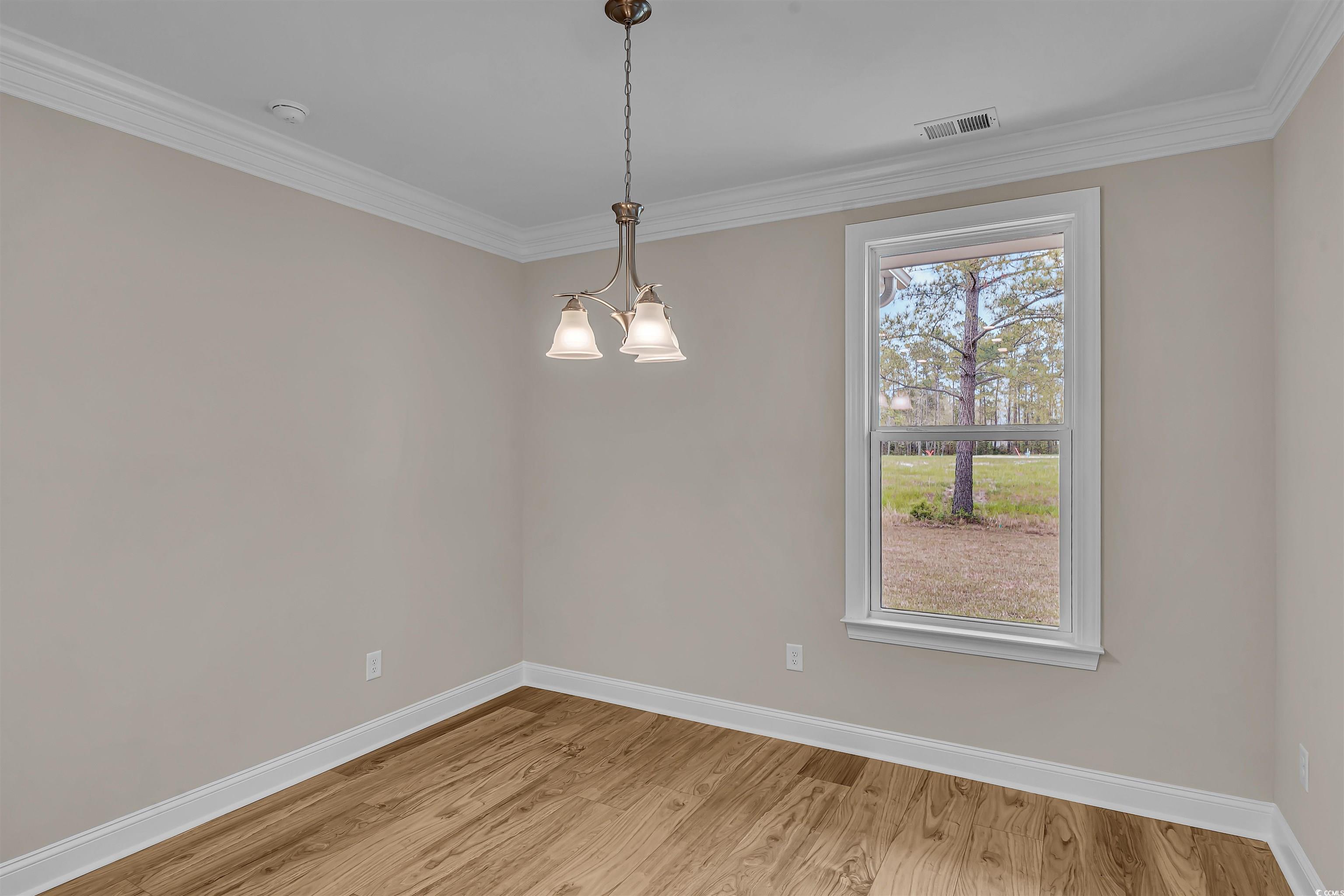 550 Beachside Circle Calabash, NC 28467 - Photo 22 of 39 Spare room with ornamental molding, light wood-type flooring, an inviting chandelier, and a healthy amount of sunlight