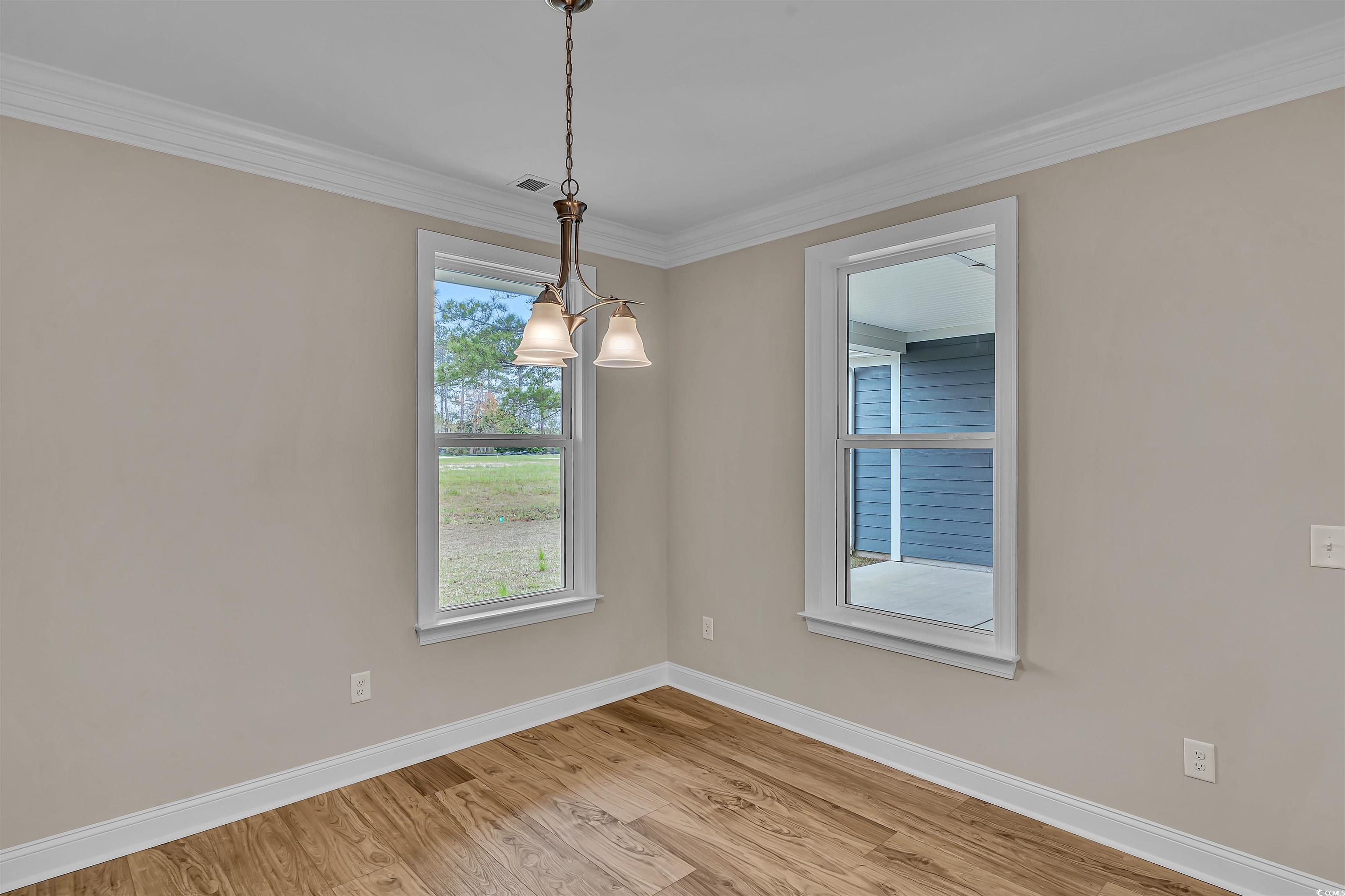 550 Beachside Circle Calabash, NC 28467 - Photo 23 of 39 Unfurnished room with light wood-type flooring, crown molding, and a notable chandelier