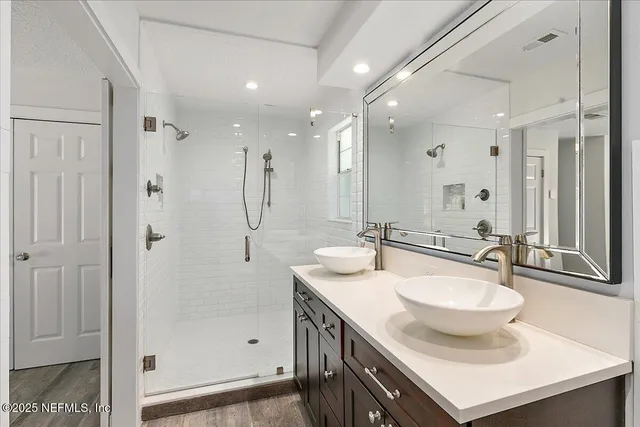 a bathroom with a sink double vanity granite tub shower and a mirror