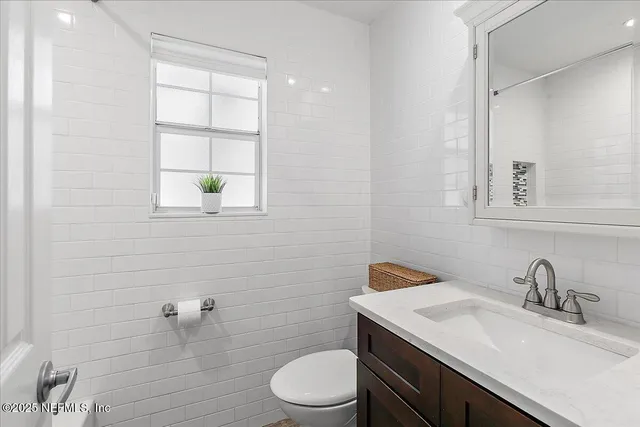 a bathroom with a granite countertop toilet a sink a mirror and a window
