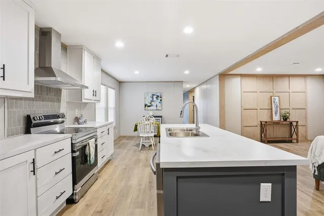 a kitchen with stainless steel appliances kitchen island granite countertop a sink a stove and cabinets