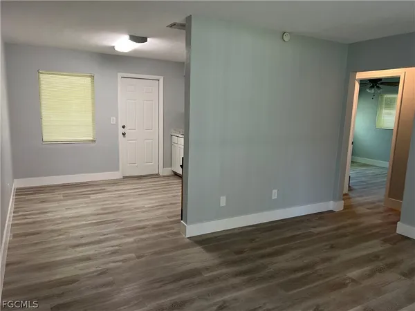 a view of an empty room with wooden floor and a window