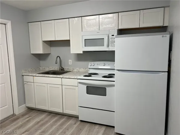 a kitchen with granite countertop white cabinets and white appliances