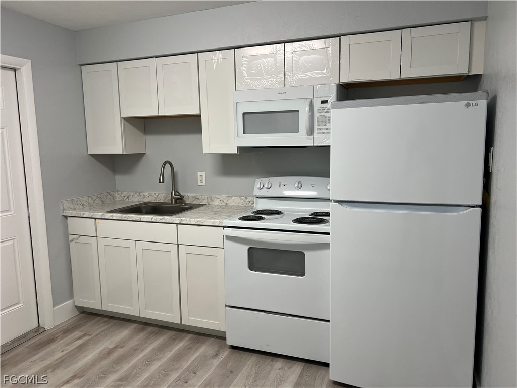 337 Tudor Drive, Unit R Cape Coral, FL 33904 - Photo 7 of 13 a kitchen with granite countertop white cabinets and white appliances