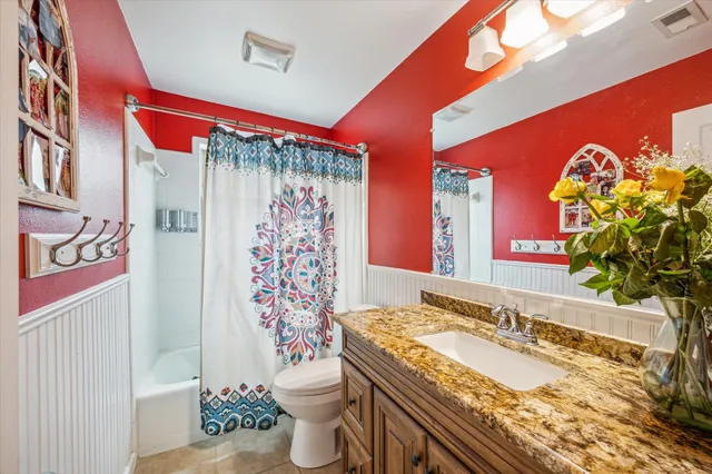 a bathroom with a granite countertop toilet sink and mirror