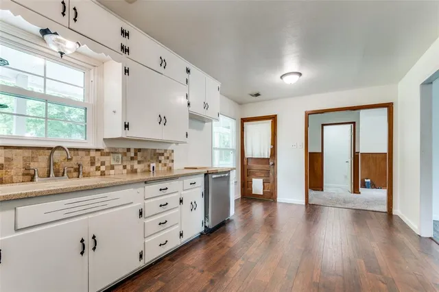 a kitchen with granite countertop a stove and white cabinets with wooden floor