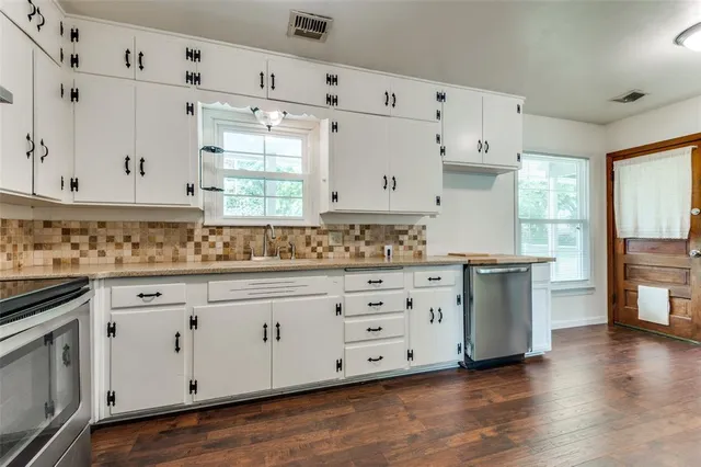 a kitchen with granite countertop white cabinets white stainless steel appliances with wooden floor