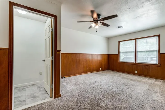 an empty room with chandelier fan and windows