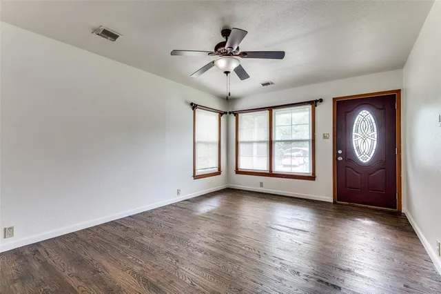 a view of an empty room with a window and wooden floor