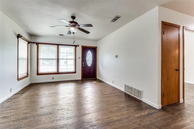 an empty room with wooden floor chandelier and windows