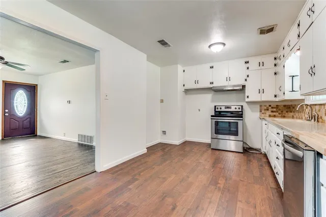 a kitchen with granite countertop a stove top oven and cabinets