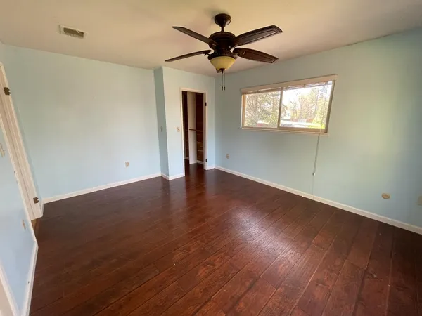 a view of an empty room with a window and wooden floor