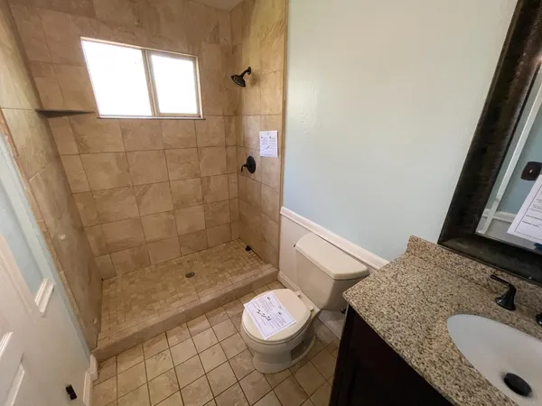 a bathroom with a granite countertop sink a toilet and shower
