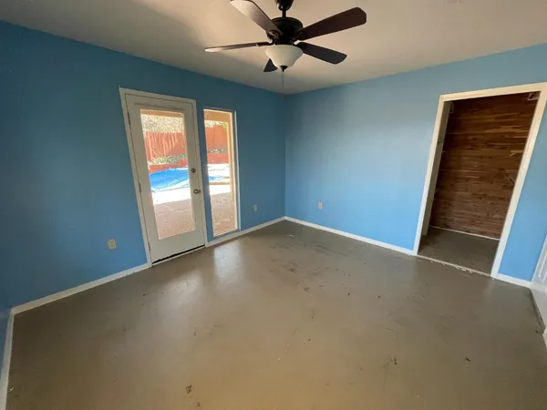 an empty room with windows and ceiling fan