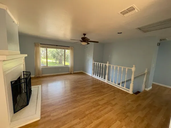 a view of a livingroom with wooden floor a ceiling fan and windows