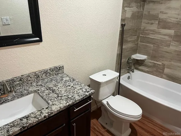 a bathroom with a granite countertop toilet sink and mirror