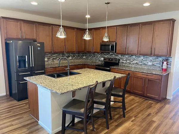 a kitchen with stainless steel appliances kitchen island granite countertop a kitchen island a stove a refrigerator a sink with a dining table and chairs