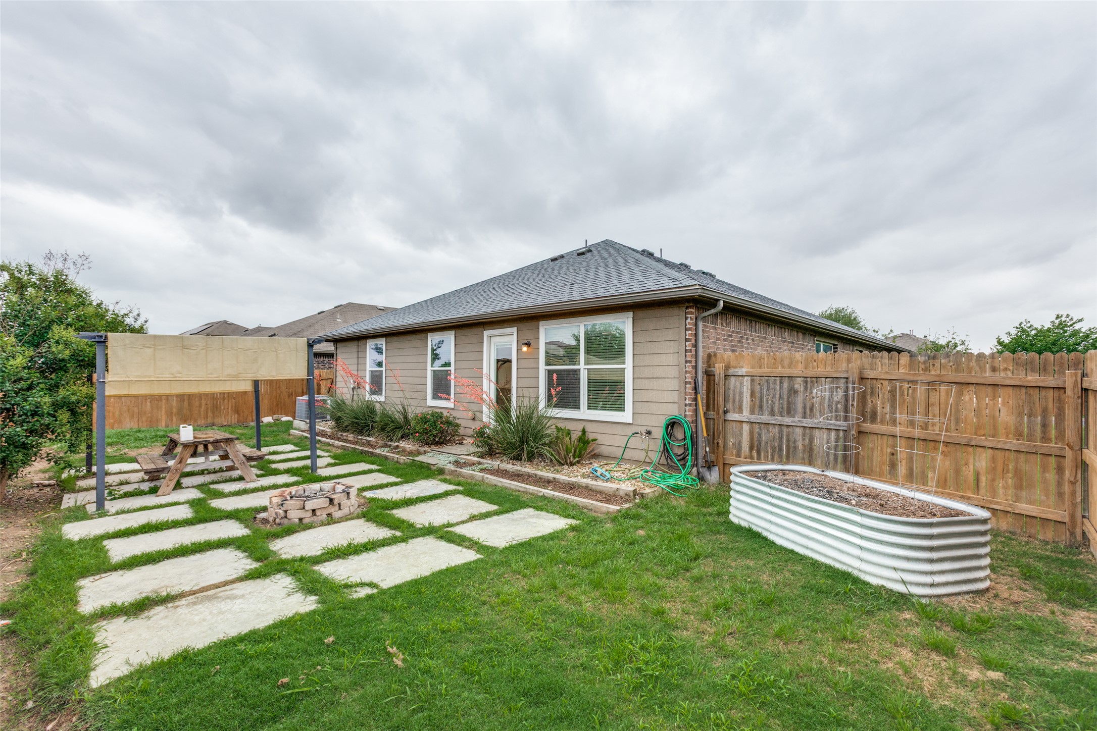 2909 Centrum Drive Austin, TX 78754 - Photo 28 of 30 The property features a backyard with a lawn, a fenced perimeter, and a patio area with a fire pit