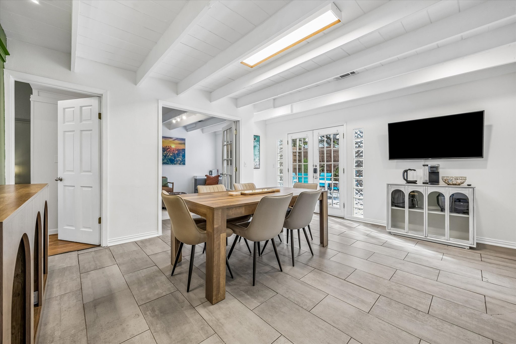 211 Lessin Lane, Unit B Austin, TX 78704 - Photo 2 of 16 The property features a dining area with exposed beam ceilings, light-colored tile flooring, and French doors leading to an outdoor area