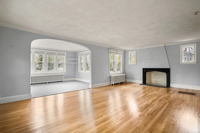 a view of an empty room with window and wooden floor