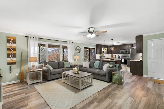 a living room with furniture kitchen view and a large window