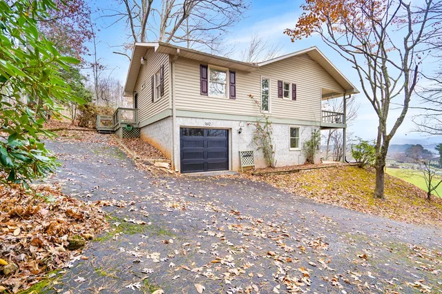 a view of a white house with a large tree and wooden fence