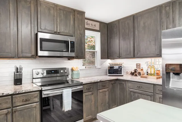 a kitchen with granite countertop kitchen island stainless steel appliances and wooden floor
