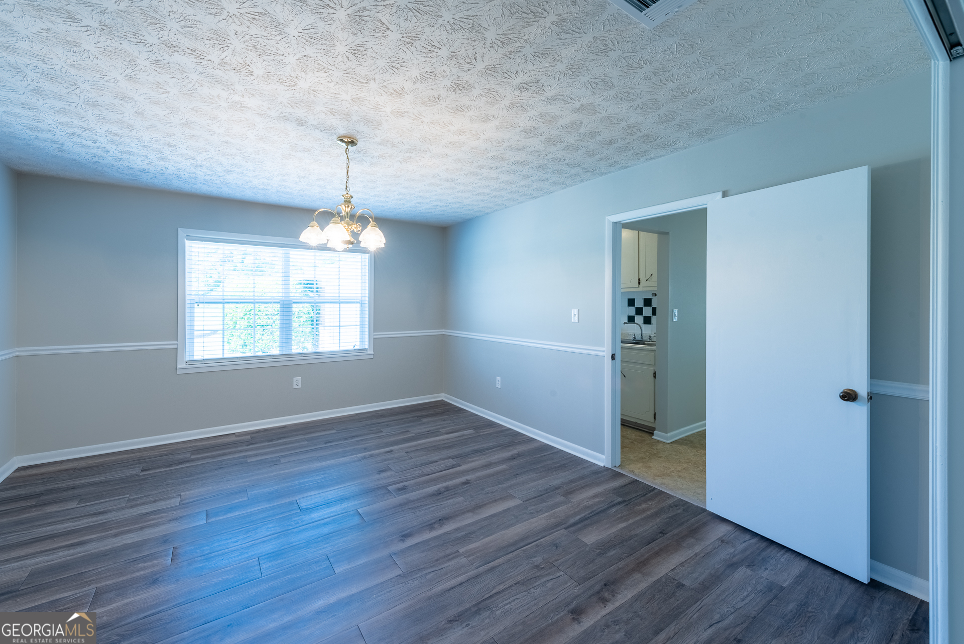 4582 St Johns Church Road Blackshear, GA 31516 - Photo 46 of 76 an empty room with wooden floor chandelier and windows