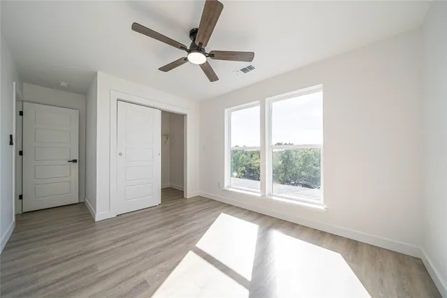 a view of a hallway with wooden floor and a bathroom