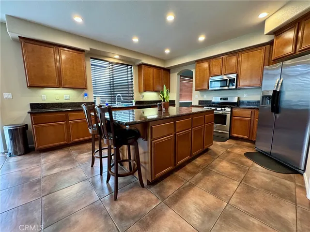 a kitchen with stainless steel appliances granite countertop wooden cabinets a dining table and chairs