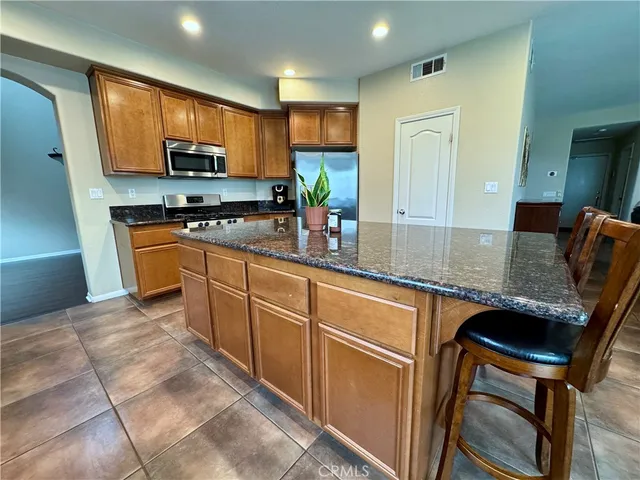 a kitchen with stainless steel appliances granite countertop a stove top oven a sink dishwasher a dining table and chairs with wooden floor