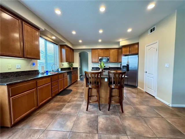 a kitchen with stainless steel appliances kitchen island granite countertop wooden cabinets a dining table and chairs
