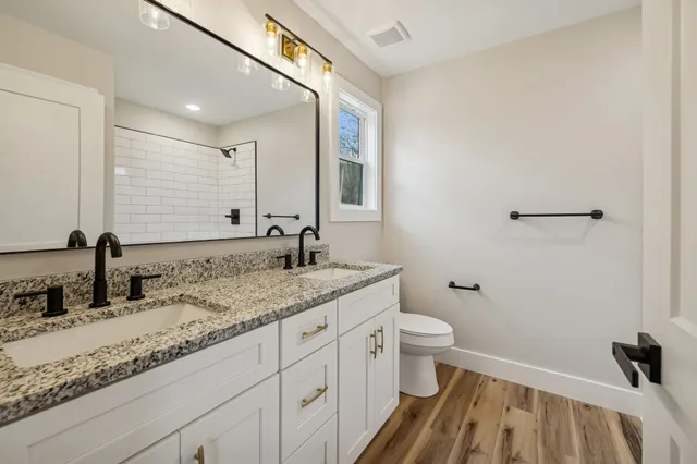 a bathroom with a granite countertop sink a toilet and a mirror