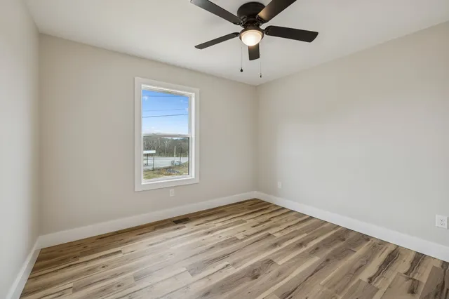 an empty room with a window and a ceiling fan