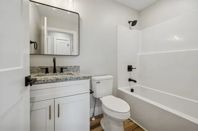 a bathroom with a granite countertop toilet sink and mirror