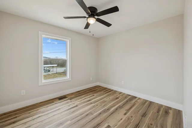 an empty room with a window and a ceiling fan