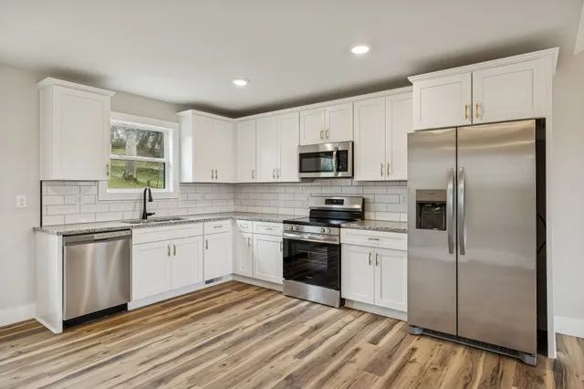 a kitchen with stainless steel appliances granite countertop a refrigerator sink and stove