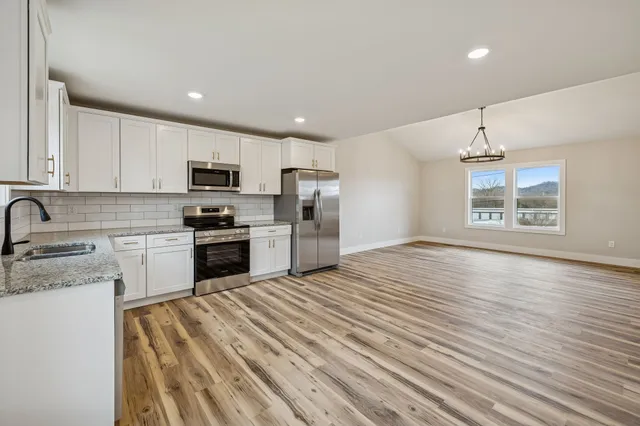 a kitchen with granite countertop a refrigerator stove top oven and sink