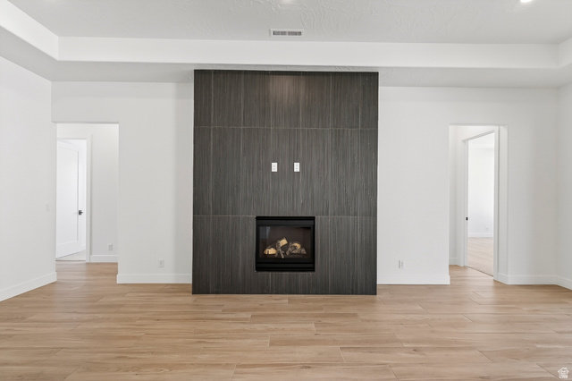2862 South Mountain Rnch Road Cedar City, UT 84720 - Photo 9 of 64 Contemporary linear fireplace with a dark-toned tile surround, complemented by light wood-finish flooring and a tray ceiling