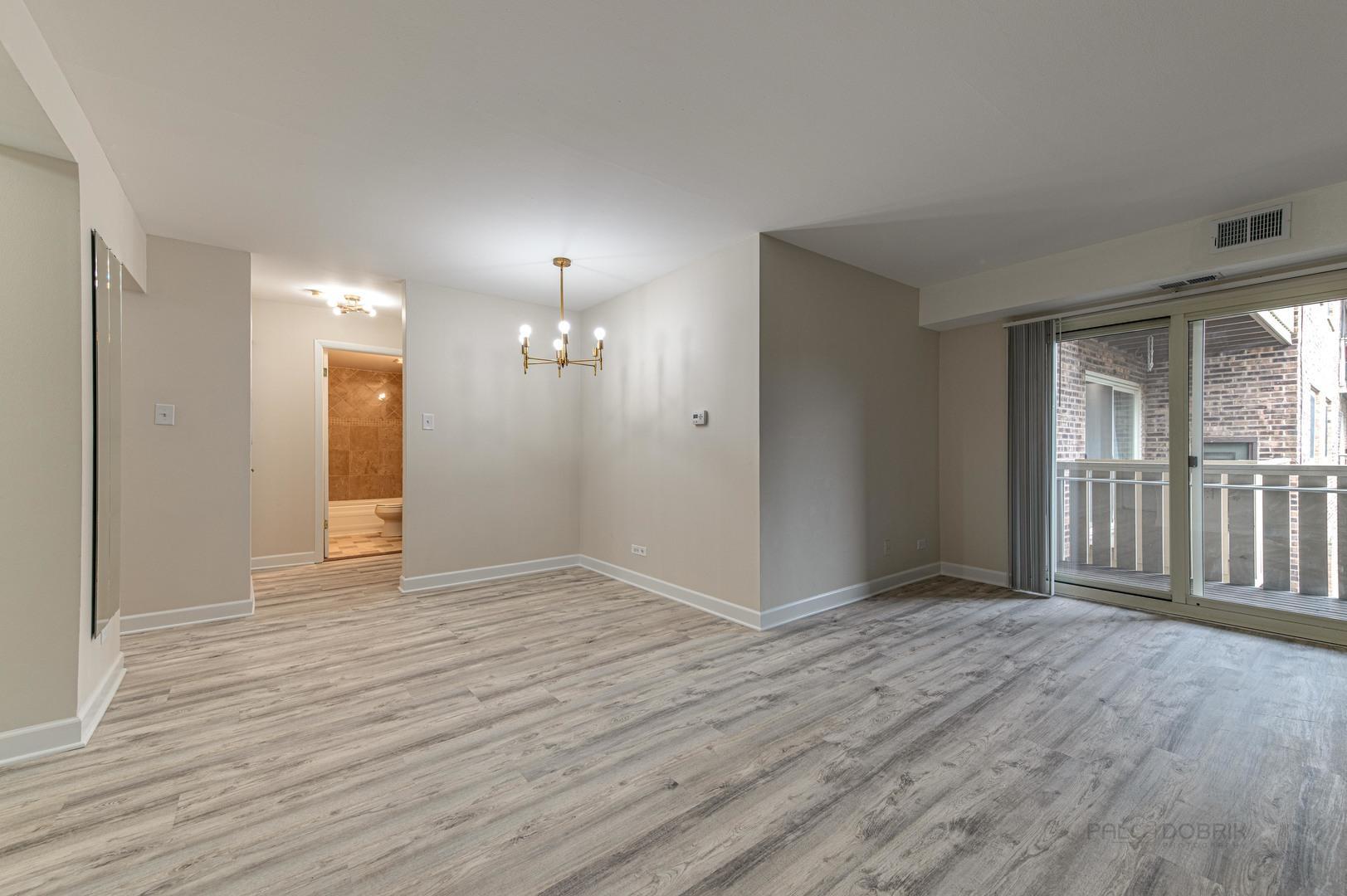 675 Grove Terrace, Unit 311 Elk Grove Village, IL 60007 - Photo 6 of 14 a view of an empty room with wooden floor and a window