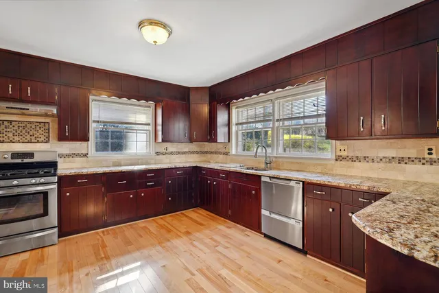 a kitchen with stainless steel appliances granite countertop wooden cabinets sink and stove top oven
