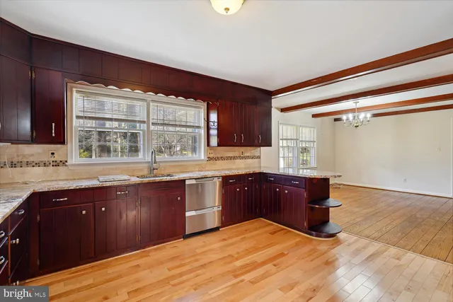 a kitchen with stainless steel appliances granite countertop a sink dishwasher and cabinets with wooden floor