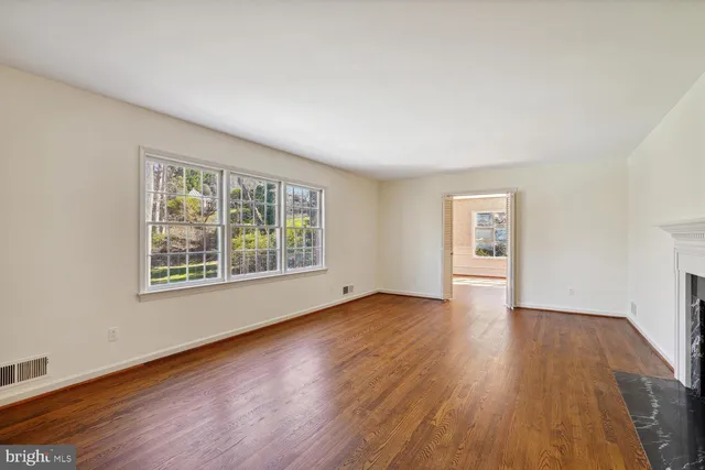 a view of an empty room with a window and wooden floor